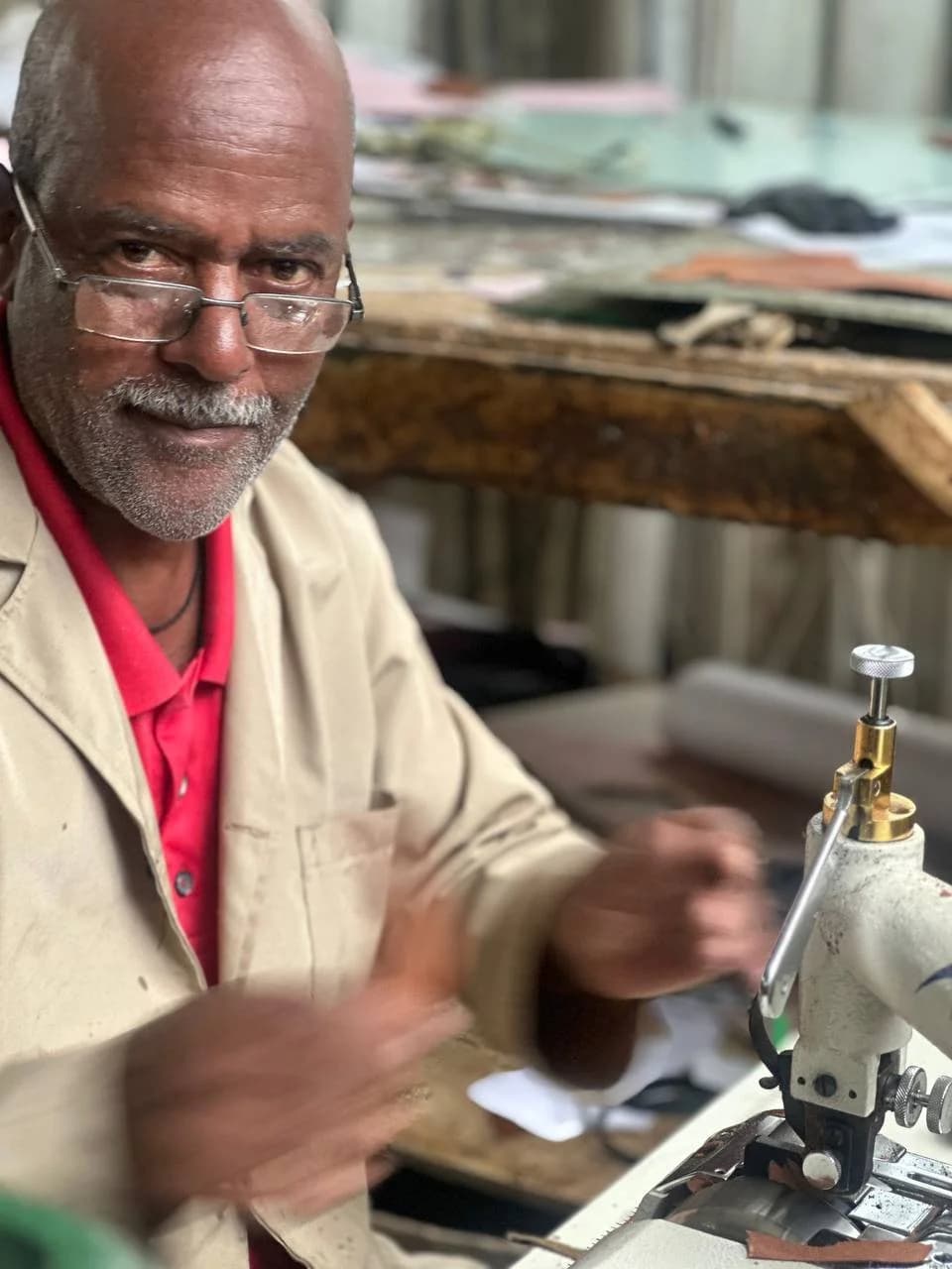 A master craftsman in glasses at an industrial sewing machine.
